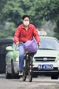 Cyclist with mouth cap with taxi on background, Guangzhou, China